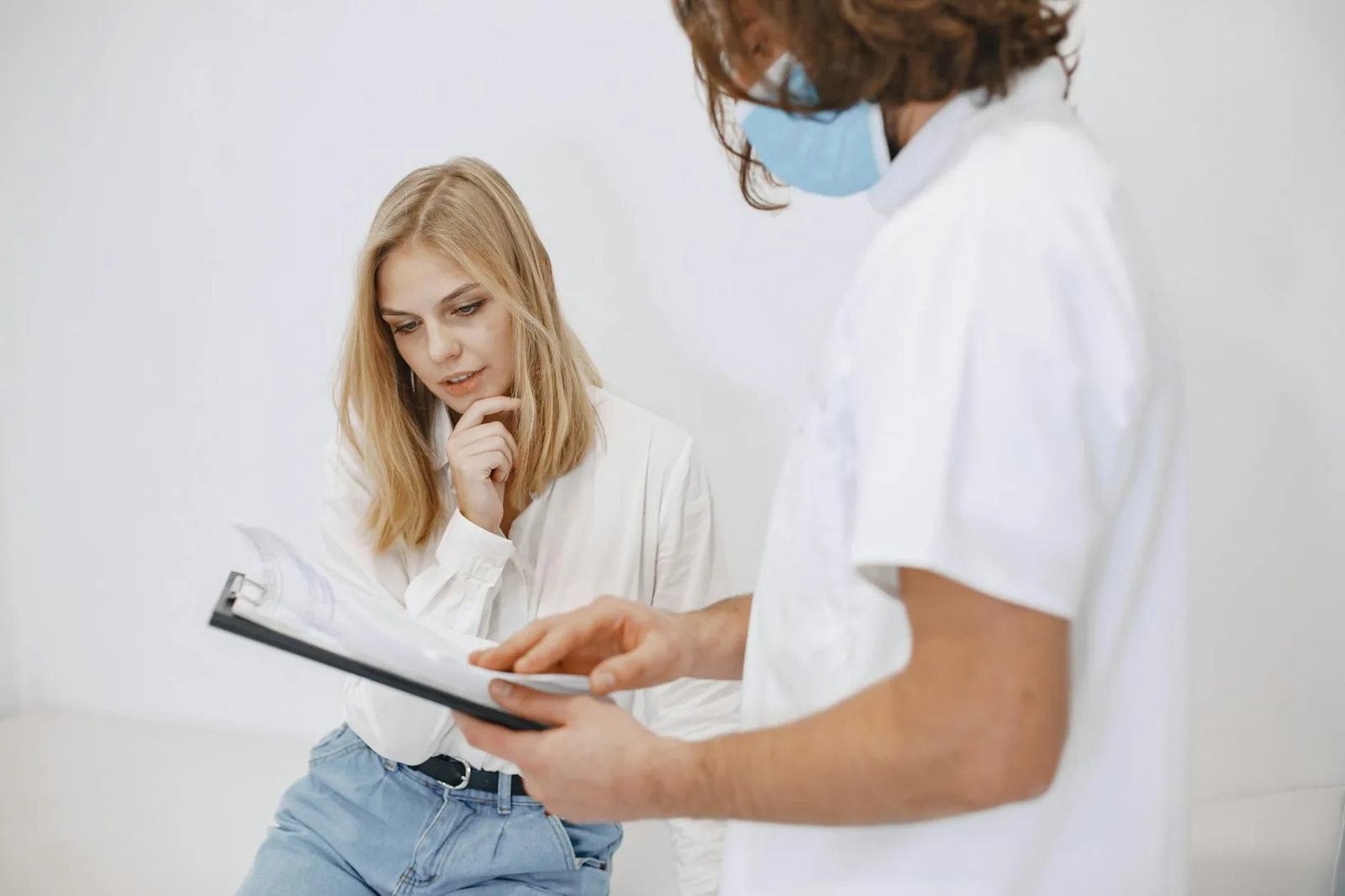 A doctor reviews a diagnosis on a clipboard with a patient, the kind of clinical interpretation an at-home kit cannot replace.