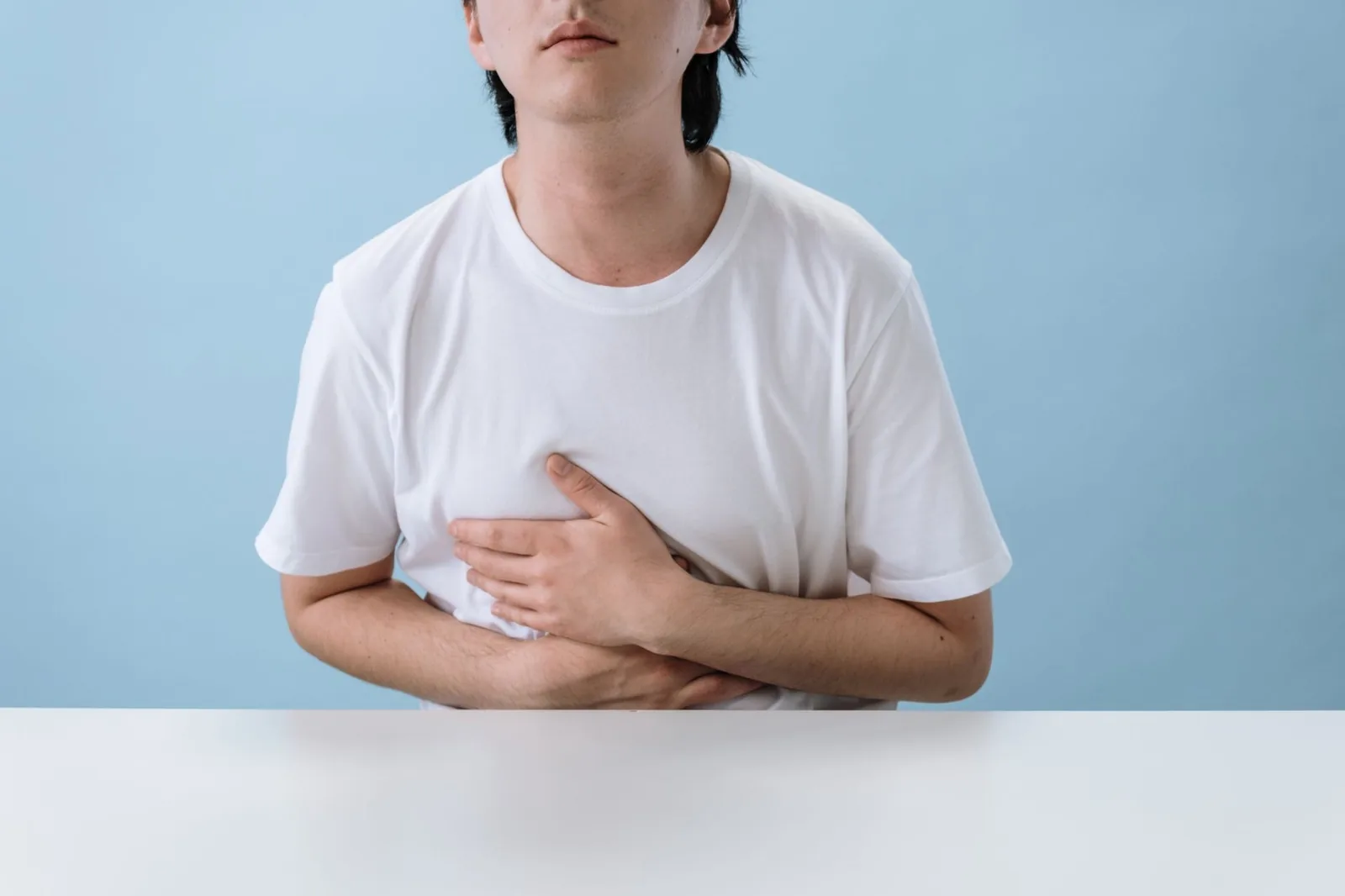 Man in a white T-shirt holding his stomach