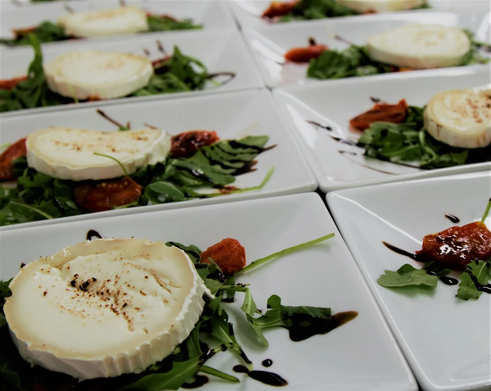Goat cheese rounds on arugula with tomatoes