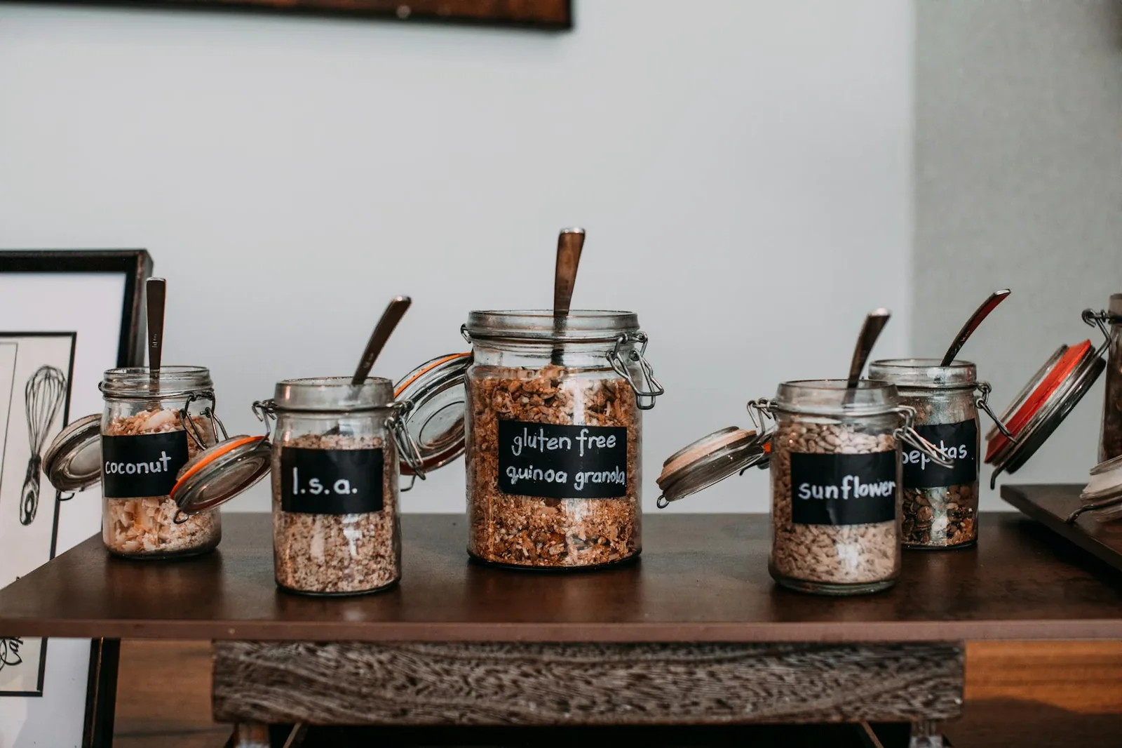 Labeled glass jars of grains and seeds on a wooden table, a reminder to read ingredients carefully.