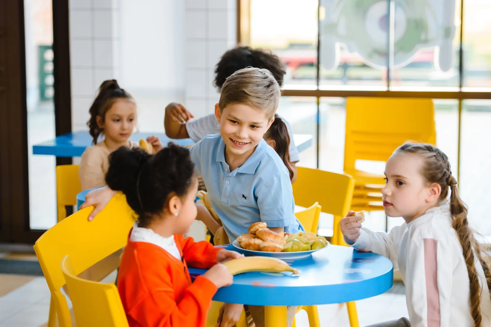 Children eating around a table in a school cafeteria