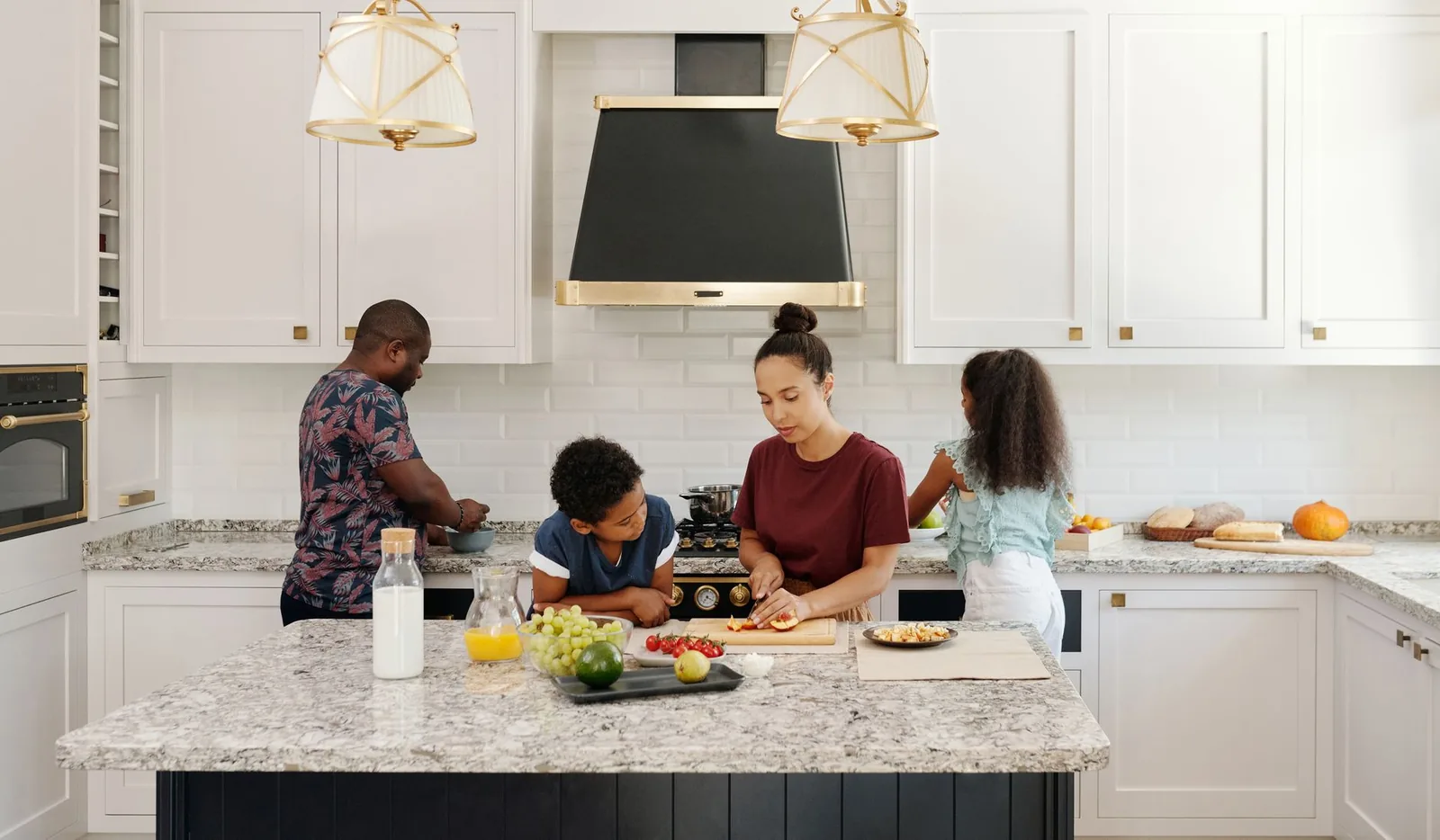 A family preparing food together at the counter of a bright, modern kitchen.