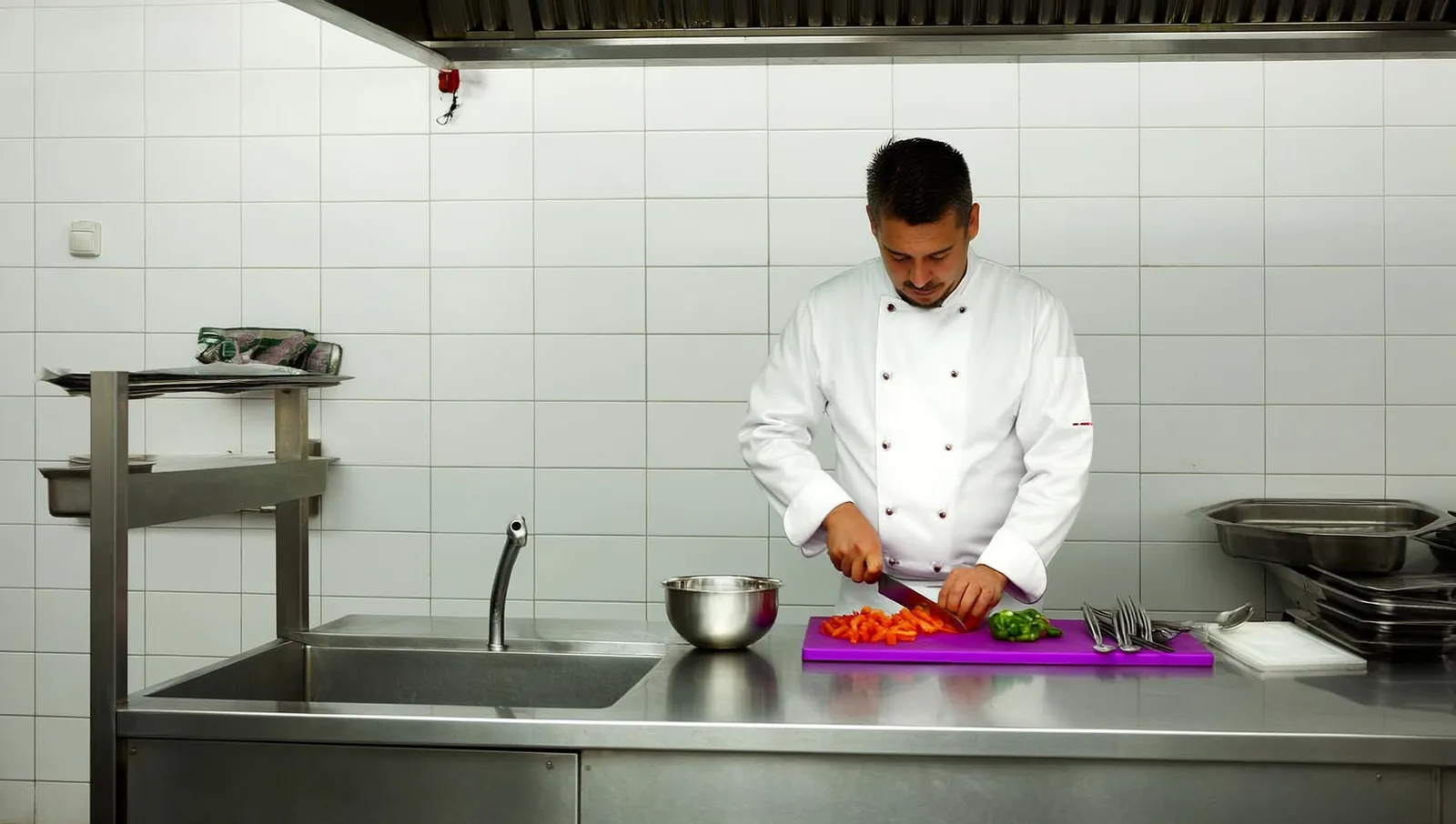 Chef slicing vegetables on a purple cutting board in a kitchen