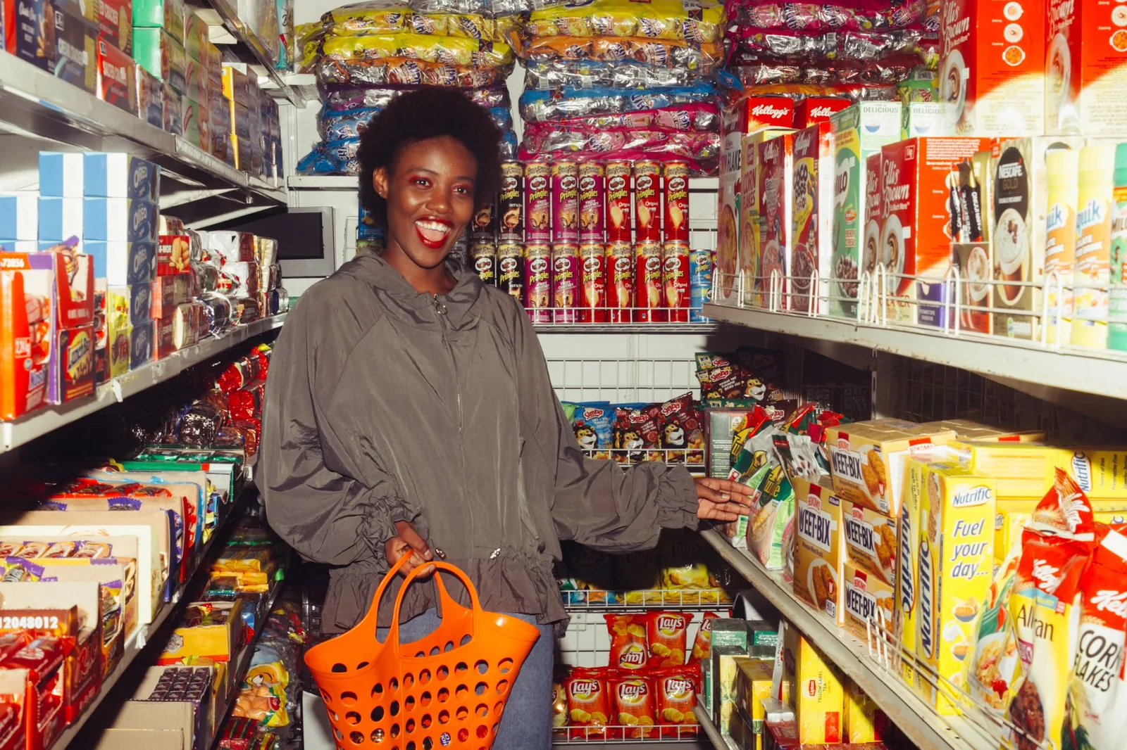 A shopper with an orange basket in a packed store aisle